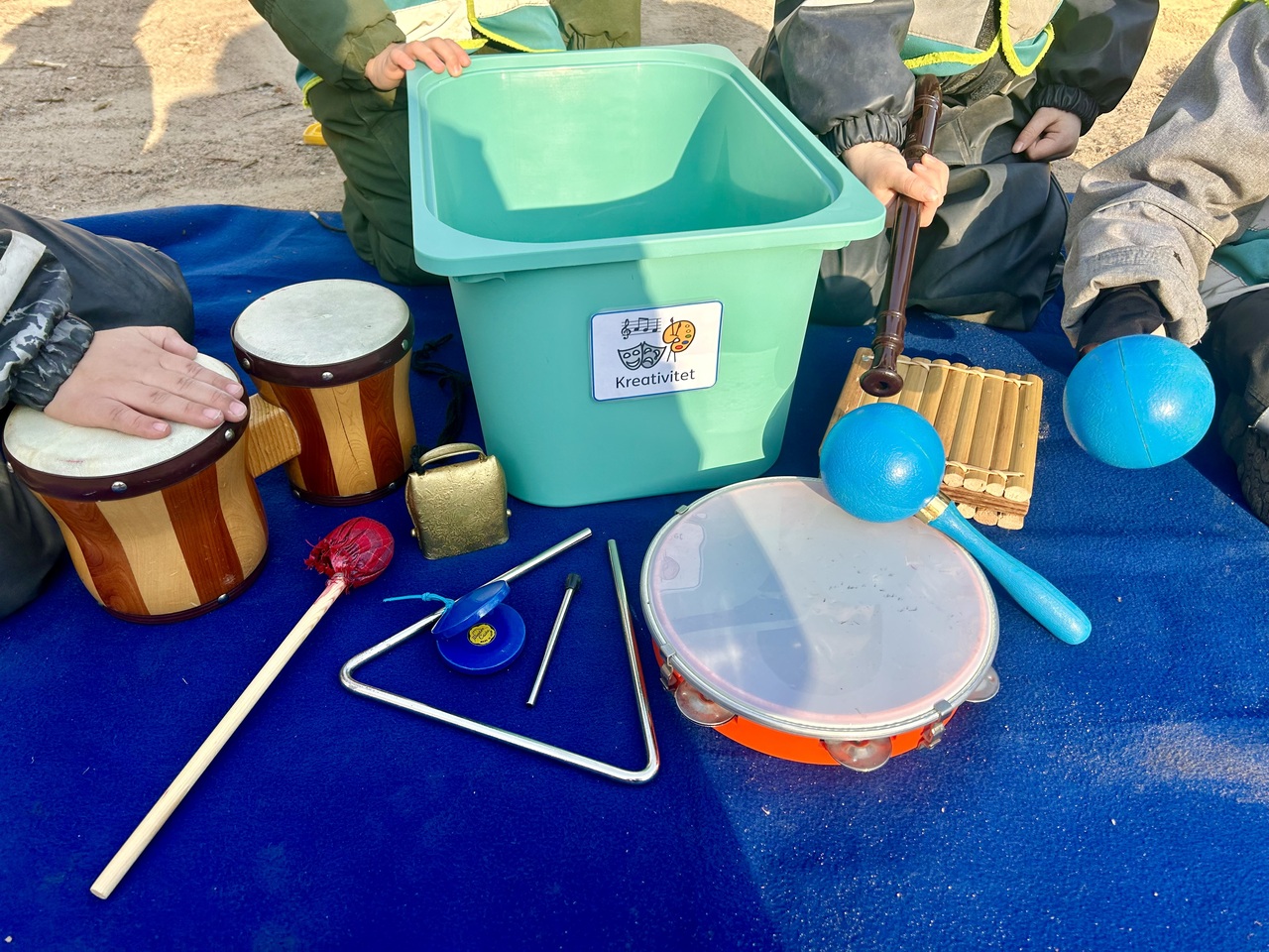 Musikstund i sandlådan där baren spelar varsitt instrument